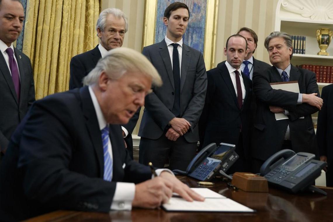 From left, former White House Chief of Staff Reince Priebus, National Trade Council adviser Peter Navarro, senior adviser Jared Kushner, policy adviser Stephen Miller and former chief strategist Steve Bannon watch as President Donald Trump signs an executive order in the Oval Office of the White House on Jan. 23, 2017, in Washington.