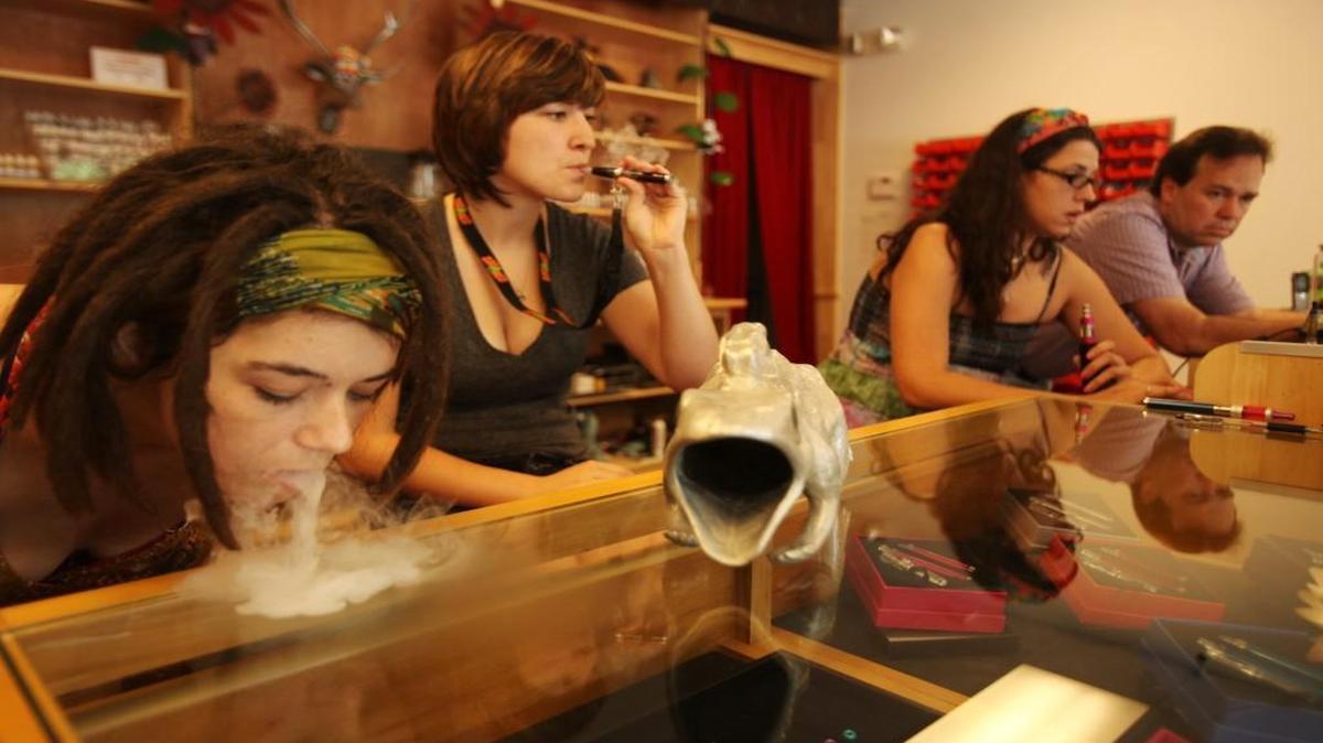 From left, Alex Lumsden exhales vapor as Cassandra Dolan, Ashley Lane and Joe Wofford vape at The Puffing Monkey/ Volcano of Raleigh Tuesday, July 23, 2013.