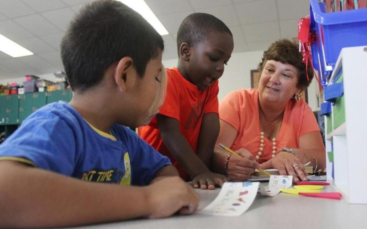 
West Smithfield Elementary School teacher assistant Donna Donovan pulls Alexander Rodriguez and Joshua Wright aside from their kindergarten class to practice their ABCs. A proposed compromise by the state Senate would keep funding for teacher assistants
