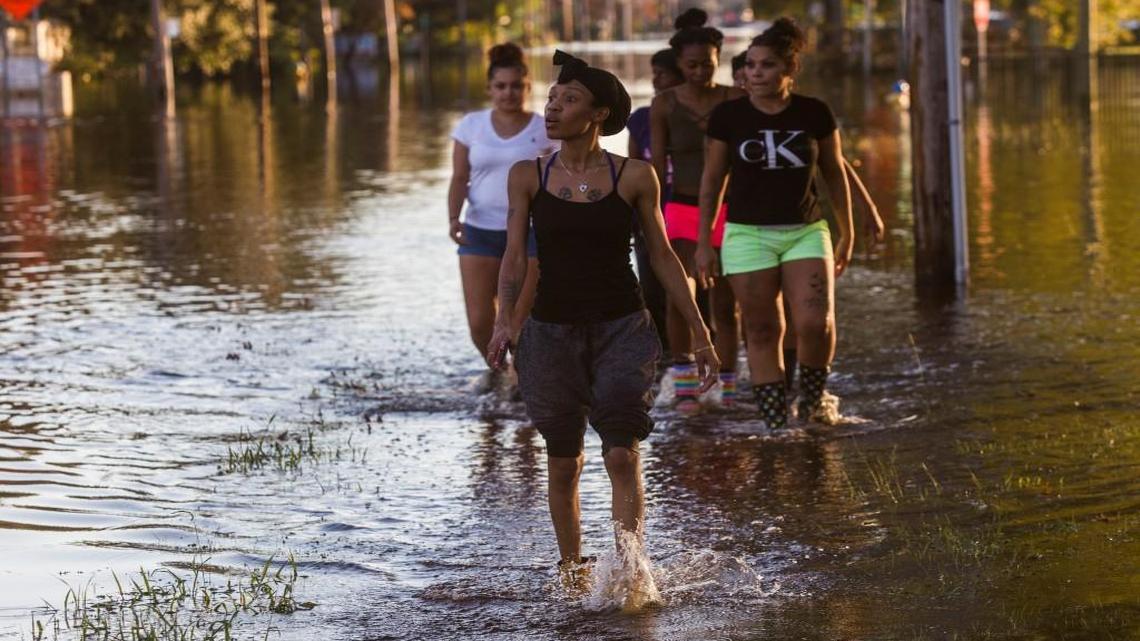 A group of Lumberton residents including Keywana Parker, foreground, walk through floodwaters after checking on their homes after Hurricane Matthew caused downed trees, power outages, a municipal water outage and widespread flooding along the Lumber River in October.