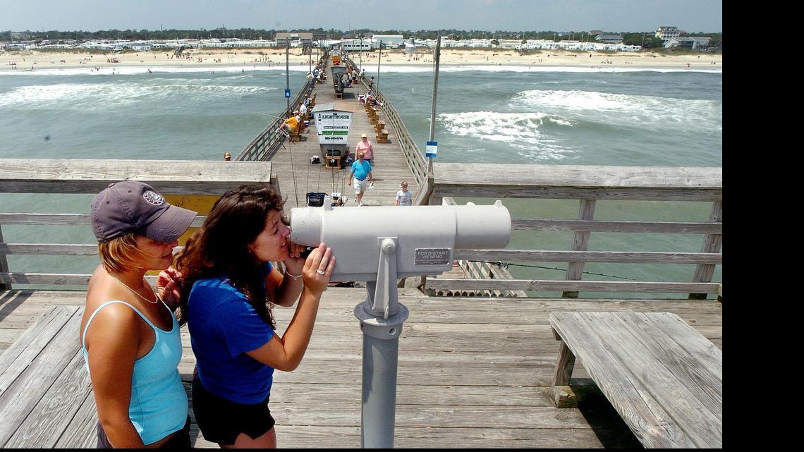 
Vacationers use a telescope on the Bogue Inlet Pier to look for the rental house they are staying in at Emerald Isle. Emerald Isle is one of four North Carolina beach towns are concerned that a Senate budget provision could put the fate of their “sand tax” districts in the hands of a few voters. 
