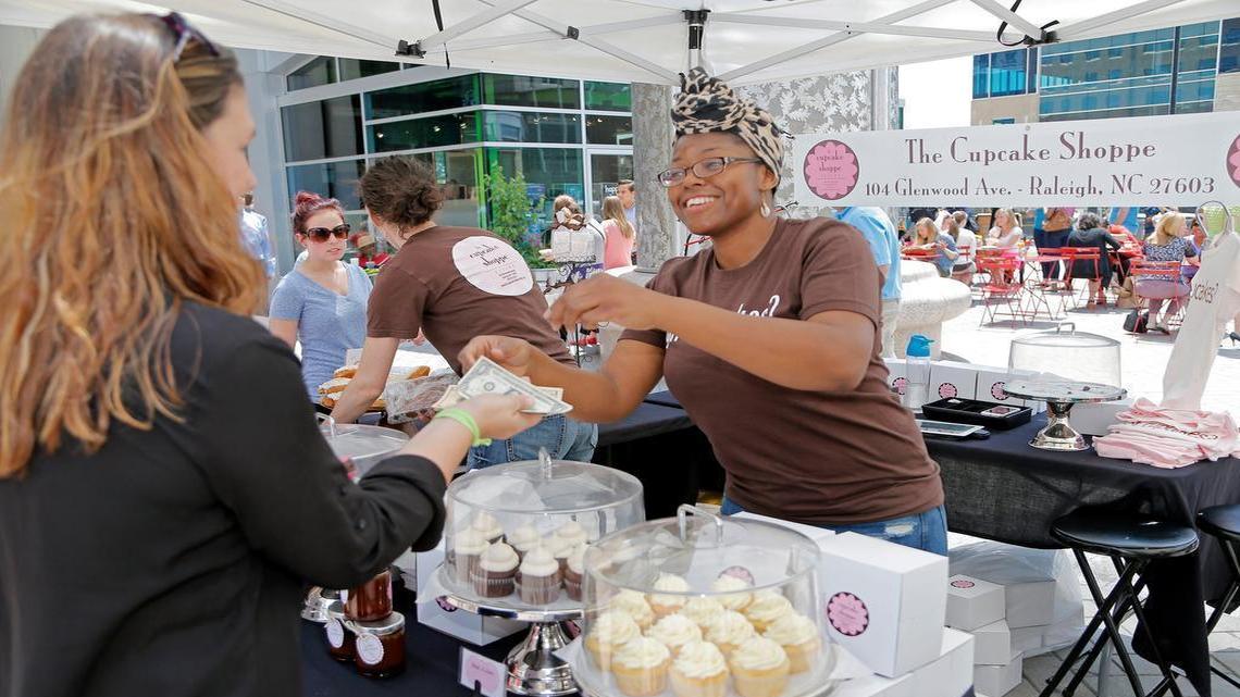 
Lucia Guity, right, with The Cupcake Shoppe cheerfully waits on a customer at the Raleigh Downtown Farmers Market in May. The market is among the events sponsored by the Downtown Raleigh Alliance, an agency largely funded by a “municipal service district” tax on downtown properties.
