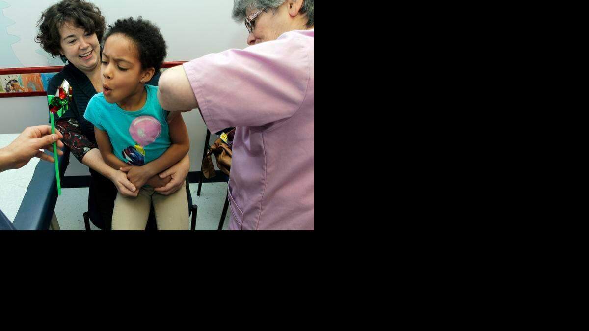
While an RN holds a pinwheel for 5yr. old patient Adjoa Colgan to blow on, RN Marie MeKeel, right, gives Adjoa her flu shot in the comfort of her mom Siobhan Colgan's lap Thursday, Dec. 12, 2013. Adjoa, from Carrboro, is a patient at Village Pediatrics at Southern Village in Chapel Hill, NC.
