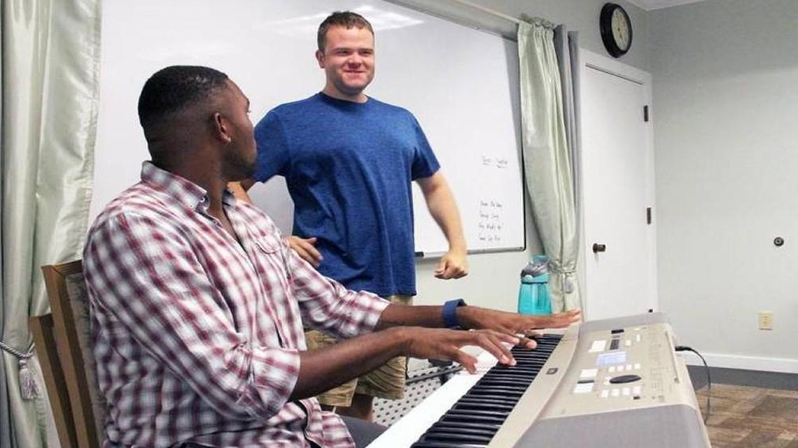 Vinnie Ireland (standing) smiles at music therapist Freddy Perkins during a group session at Extraordinary Ventures in Chapel Hill on July 18.
