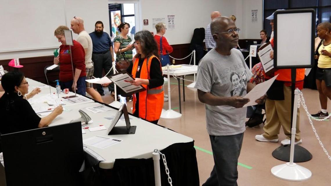 A Wake county voter in right foreground moves toward the voting booth after obtaining his ballot at the Herbert C. Young Community Center early voting site in Cary, NC Friday, March 11, 2016.