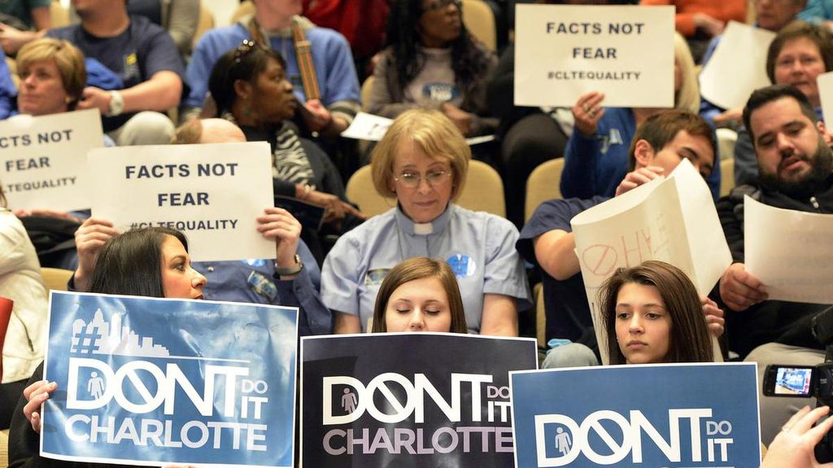 Supporters and opponents of the proposed non-discrimination ordinance hold up signs inside the Charlotte Mecklenburg Government Center prior to the start of a City Council meeting last year.