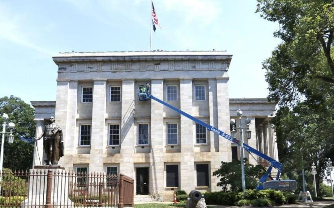 A workman for Midwest Maintenance, Inc. of Ohio, on lift in background, does finish exterior painting to a renovated window on the top floor south side above the old House chamber of the NC Capitol building Tuesday, July 26, 2016. Although some money was already approved by the NC Legislature for renovations to the NC Capitol building, the NC State Capitol Foundation has secured more funds from the state budget to renovate even more of the ca. 1840 structure.