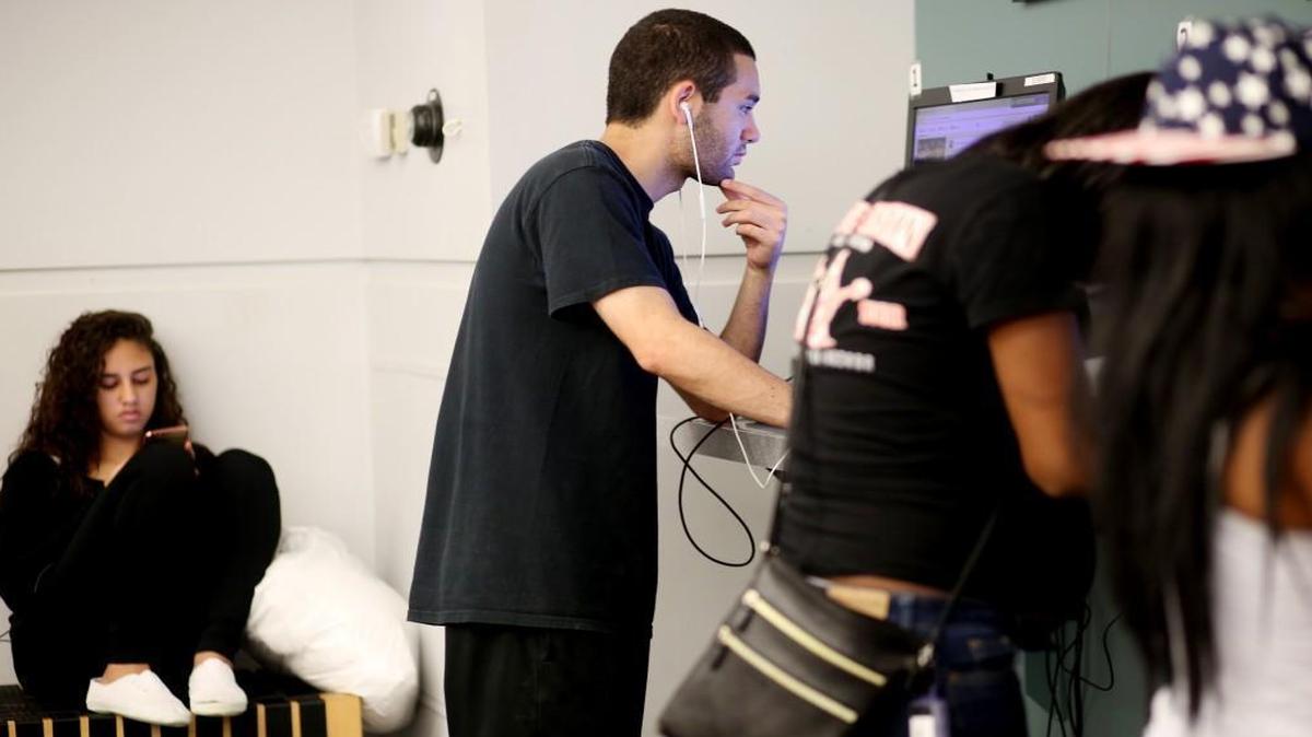 Nick Gonzalez, center, and Iris Hernandez, far left, use the Wi-Fi at Express Library Fayetteville Street in Raleigh on Wednesday afternoon, Oct. 19, 2016. Gonzalez says he comes to the library daily to use the internet because his only access is his smartphone. More than one in five households in North Carolina lack internet service.