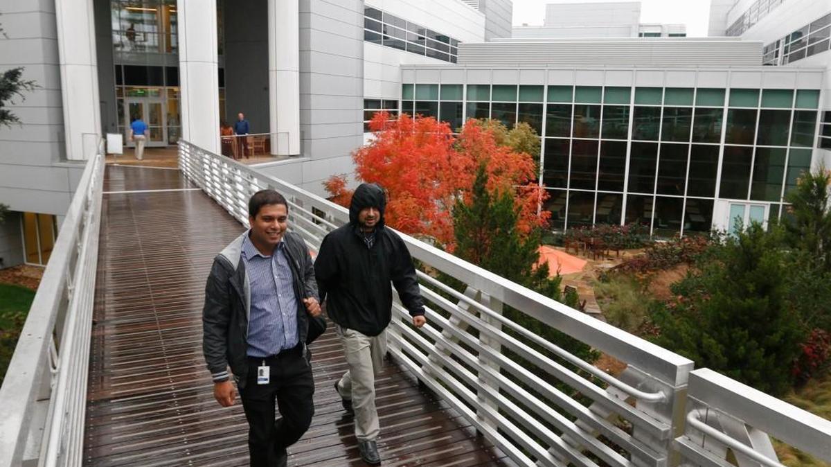 Fidelity Investments employees walk an elevated ramp from their Fidelity Investments/RTP main building complex on 17 acres at 100 New Millennium Way to the parking garage Tuesday, Oct. 27, 2015. Earlier that day, Fidelity Investments, a financial services firm, announced that it would create 600 new jobs, mostly in IT and related fields in its Cary, NC, and Durham, NC, offices within three years.