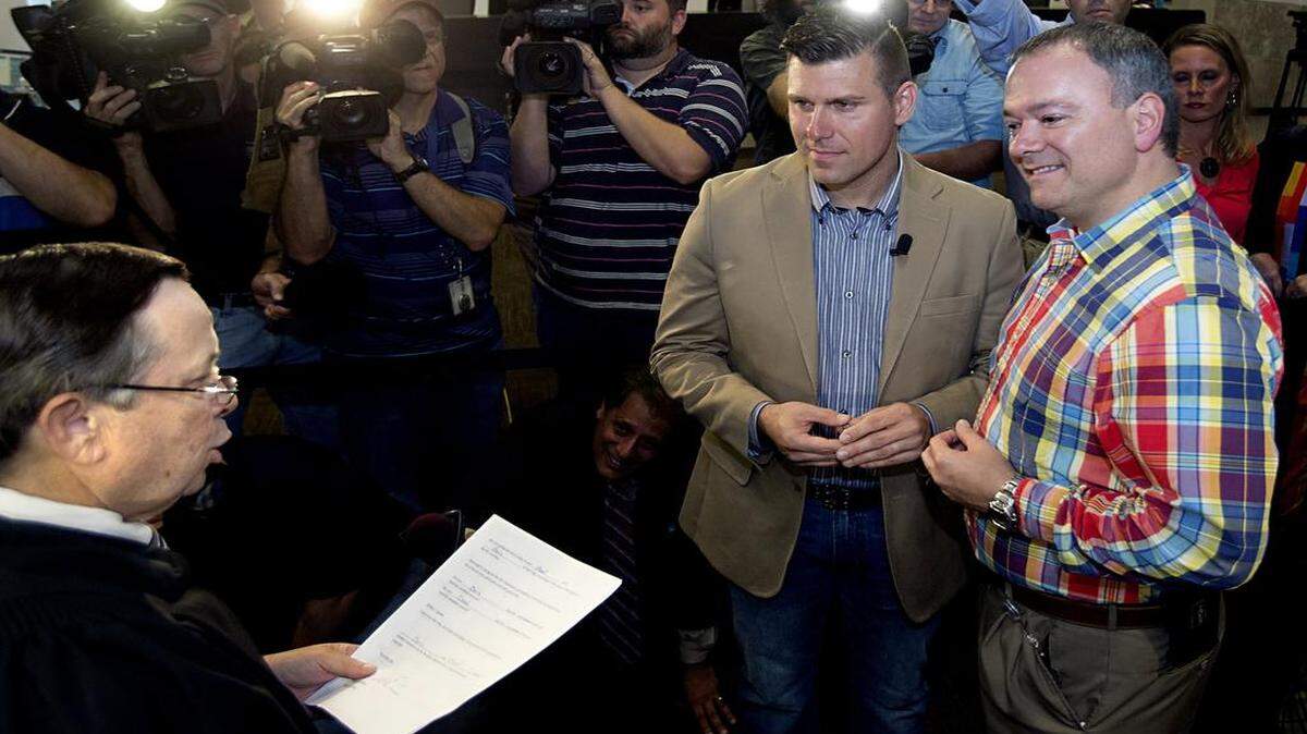 
Chad Briggs (left) and his partner Chris Creech exchange wedding vows as Chief Magistrate Dexter Williams, left, presides at the Wake County Courthouse in Raleigh on October 10, 2014. They were the first gay couple to be married in Wake County.
