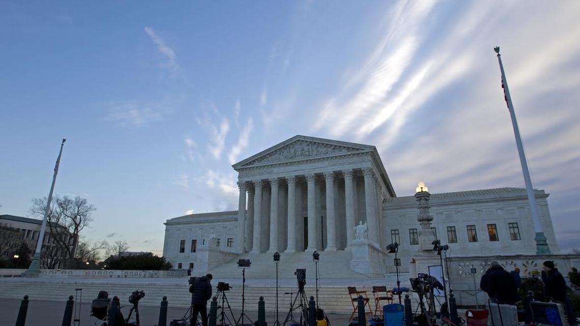 Members of the news media gather outside the Supreme Court in Washington.