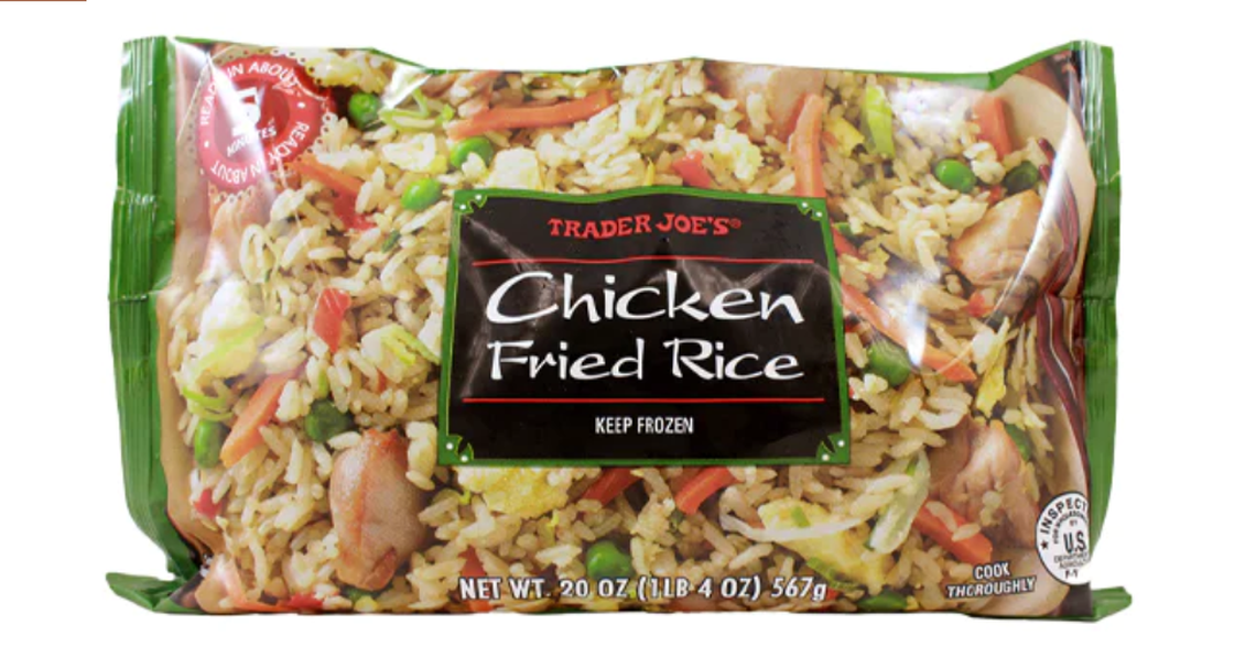 A 20-ounce bag of Trader Joe’s frozen Chicken Fried Rice, featuring a vibrant photo of the meal with visible pieces of chicken, peas, and carrots. The packaging includes a red seal noting it is ready in about five minutes and instructions to keep the product frozen.