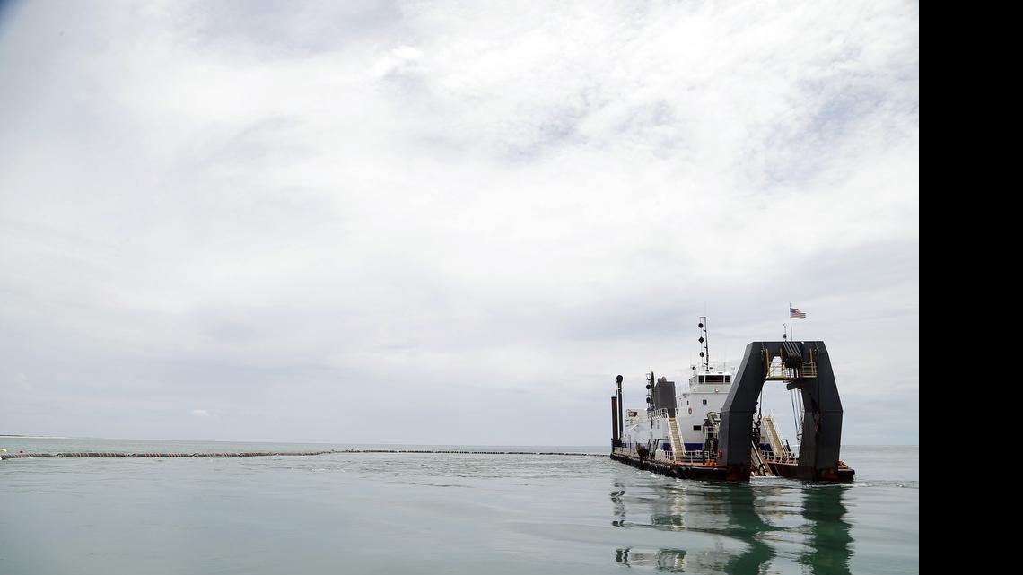 
The dredge Savannah is reflected in the calm waters as it digs up sand from the shipping channel at the port at Morehead City on Wednesday, June 3, 2015. The state of North Carolina and the U.S. Army Corps of Engineers are trying to figure out a way to keep the shipping lanes at the State Port at Morehead City deep enough. Some dredging operations like this one are going on, but more is needed to keep up with the sand that is filling in the channel. 
