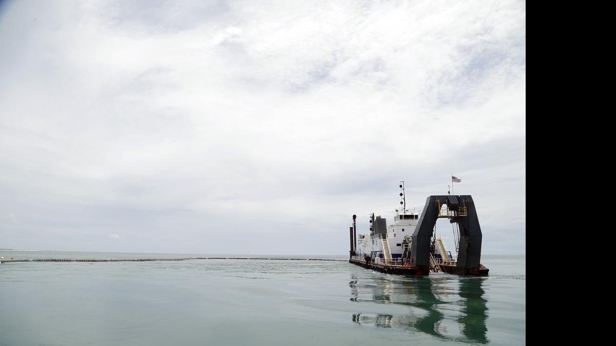 
The dredge Savannah is reflected in the calm waters as it digs up sand from the shipping channel at the port at Morehead City on Wednesday, June 3, 2015. The state of North Carolina and the U.S. Army Corps of Engineers are trying to figure out a way to keep the shipping lanes at the State Port at Morehead City deep enough. Some dredging operations like this one are going on, but more is needed to keep up with the sand that is filling in the channel. 

