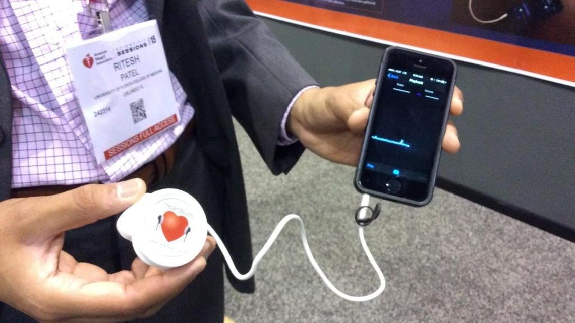 One of the study authors shows how HeartBuds works with smartphone, during the American Heart Association scientific sessions in Orlando, Fla.