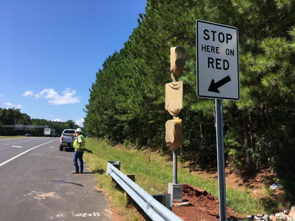 Workers install a ramp signal at the ramp from Creedmoor Road on to westbound Interstate 540 in 2017. After being turned off during the COVID-19 pandemic, the signals will be used again during the morning commute starting Tuesday, Sept. 28.