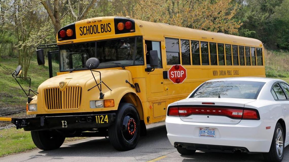 A car drives past a school bus fitted with exterior cameras while the stop arm is extended during a demonstration of the new cameras in 2015.
