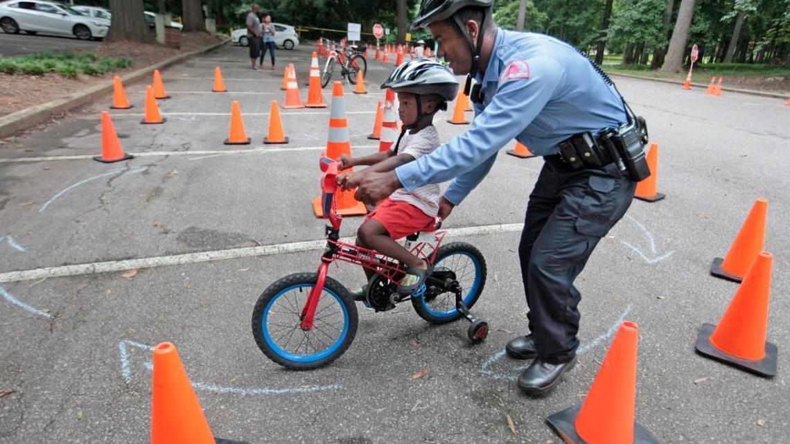 Cameron Council, 4, gets some steering and balance help on his bicycle from Raleigh police officer Charles Kay during a neighborhood bike rodeo in July 2016. Raleigh police officers taught kids about bicycle safety, hand signals and negotiating bicycle courses, and the kids got free bicycle helmets.