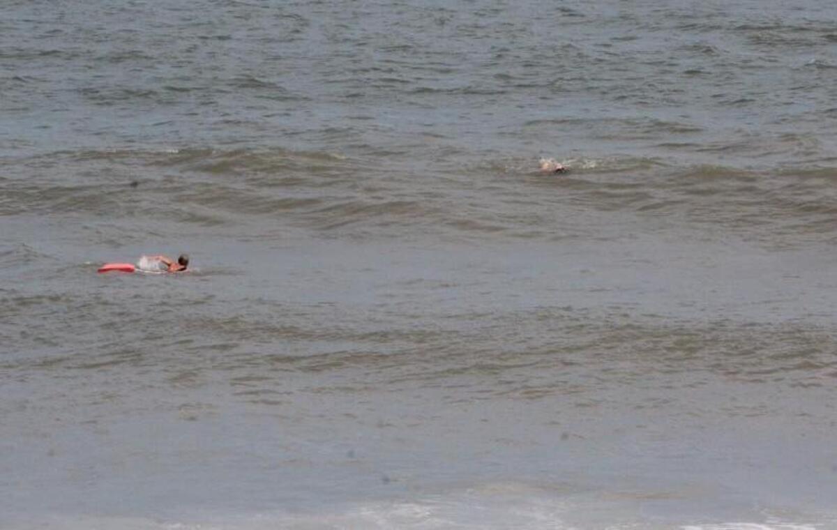 Lifeguard Bryan Veals, left, swims out to help a girl caught in a rip current at Carolina Beach on Monday.