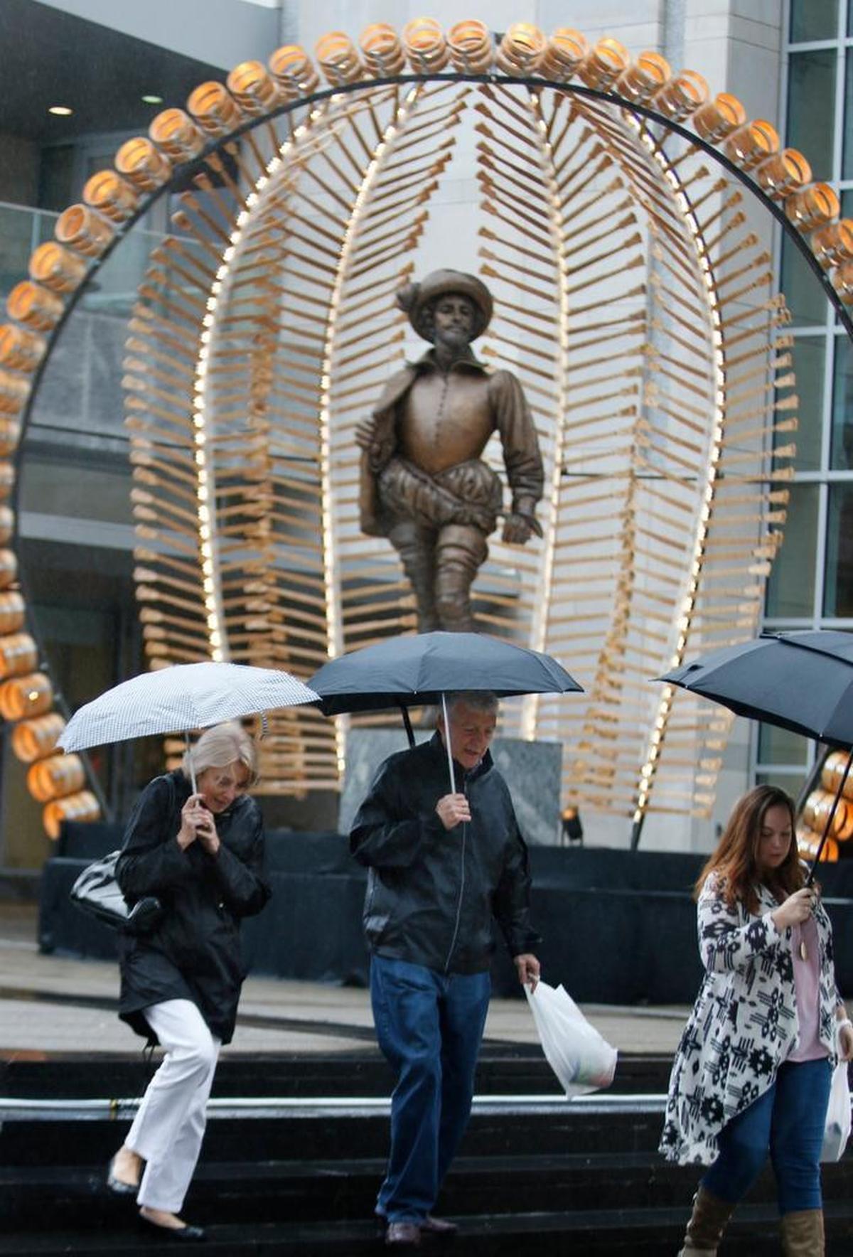 From left, Patricia Oldfield and husband David Oldfield, both visiting from England and family friend Lauren Jones of Raleigh had to put up their umbrellas as they left the Raleigh Convention Center October 2, 2015. Heavy rain forced most of the 2015 Wide Open Bluegrass Festival outdoor venues to move inside.