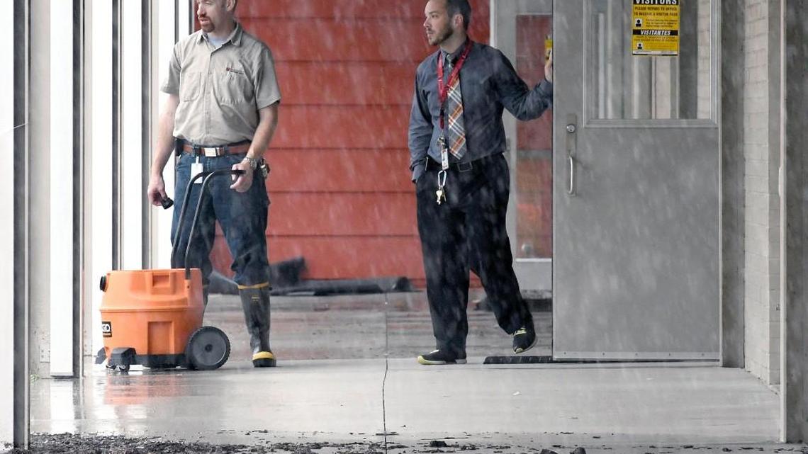 A maintenance worker empties water out of a shop vac as a fellow employee watches the downpour at the Vernon Malone College and Career Academy in Raleigh, N.C., Tuesday, April 25, 2017. The school had several rooms and a back hallway flooded with about two inches of water from the heavy rains associated with a slow moving cold front this morning.