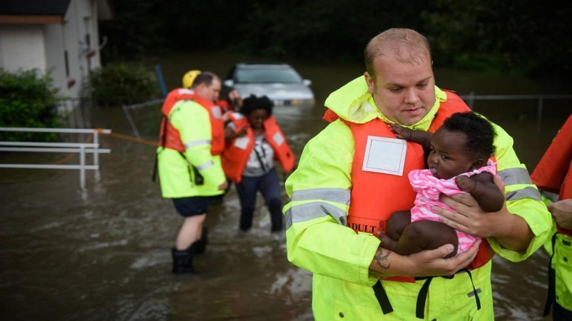 Firefighter A.J. Brown carries Mechelle Borgelin as her mother Candice Council is helped by other firefighters at their flooded home on Robeson Street in Fayetteville, NC Thursday, Sept. 29, 2016.