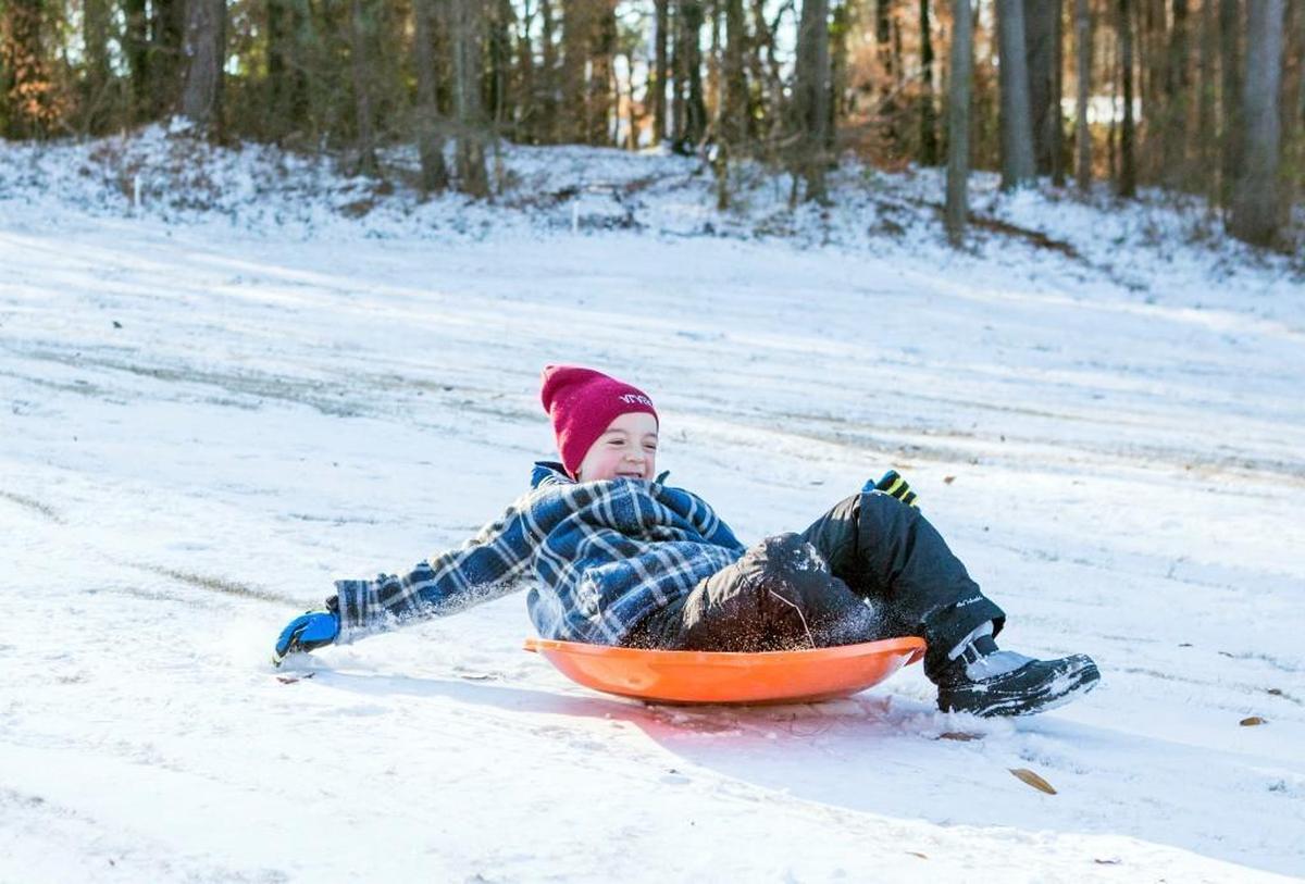 Phoenix Coker slides down a popular sledding hill by the Hillandale Golf Course on Thursday, Jan. 4, 2017, after snow Wednesday night cancelled school in Durham County.