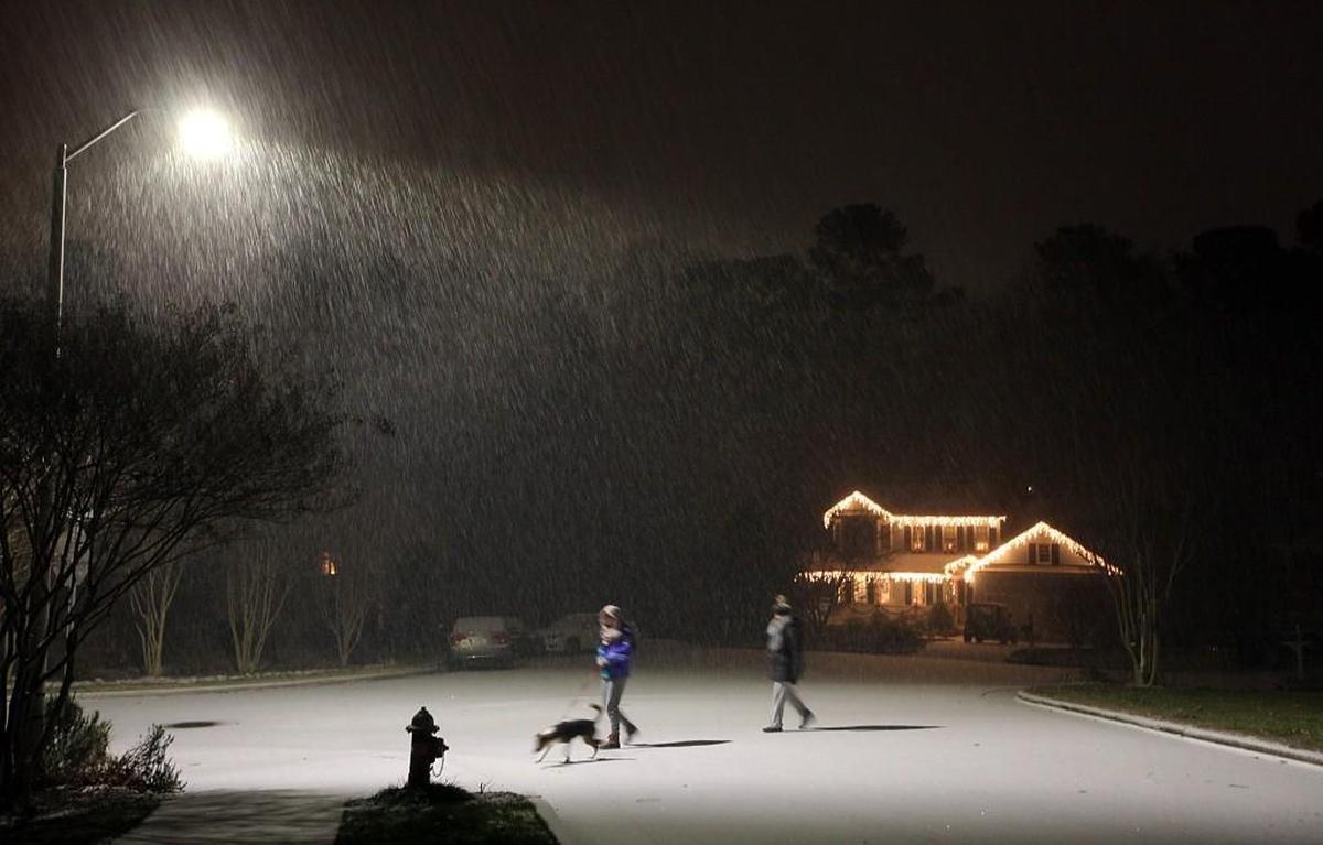 As the snow begins to fall, neighbors walk their dog in Cary at about 9 p.m. Wednesday, Dec. 3, 2018.