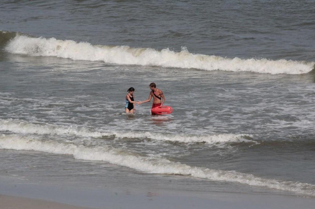 Lifeguard Bryan Veals, right, shakes hands with a girl after saving her from a rip current at Carolina Beach on Monday.