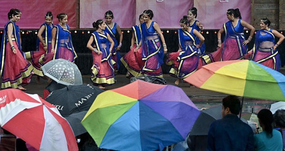 Dancers perform as spectators try to keep dry in a driving rain during the Cary Diwali celebration at the Koko Booth Amphitheatre in Cary, N.C. October 10, 2015.