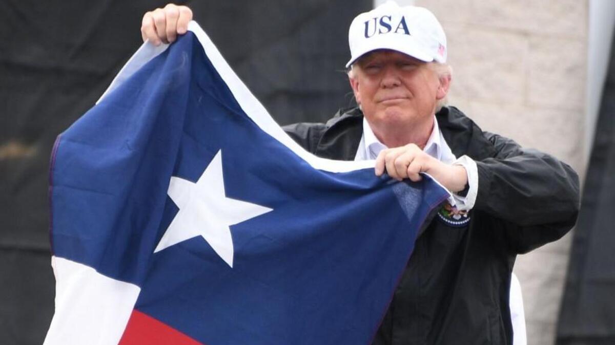 US President Donald Trump holds the state flag of Texas outside of the Annaville Fire House after attending a briefing on Hurricane Harvey in Corpus Christi, Texas on August 29, 2017. President Donald Trump flew into storm-ravaged Texas Tuesday in a show of solidarity and leadership in the face of the deadly devastation wrought by Harvey – as the battered US Gulf Coast braces for even more torrential rain.