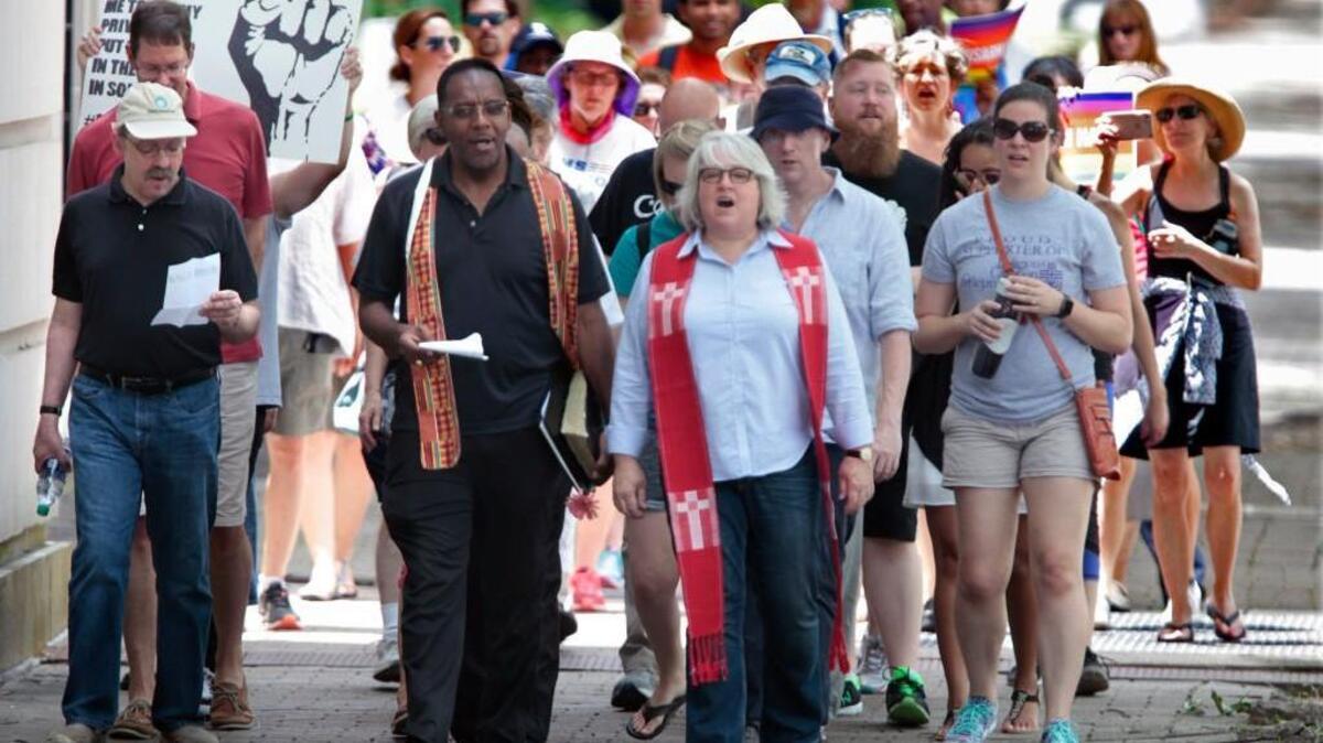 From center left, the Reverends Curtis Gatewood and Nancy Petty lead a group of about 60 protestors down Hillsborough Street near Glenwood Avenue in Raleigh, NC to the State Capitol in a March for Justice Saturday, July 9 2016. They were all part of a larger group that attended a prayer vigil of Lament and Reconciliation at Pullen Memorial Baptist Church earlier for civilian and police victims of violence this past week.
