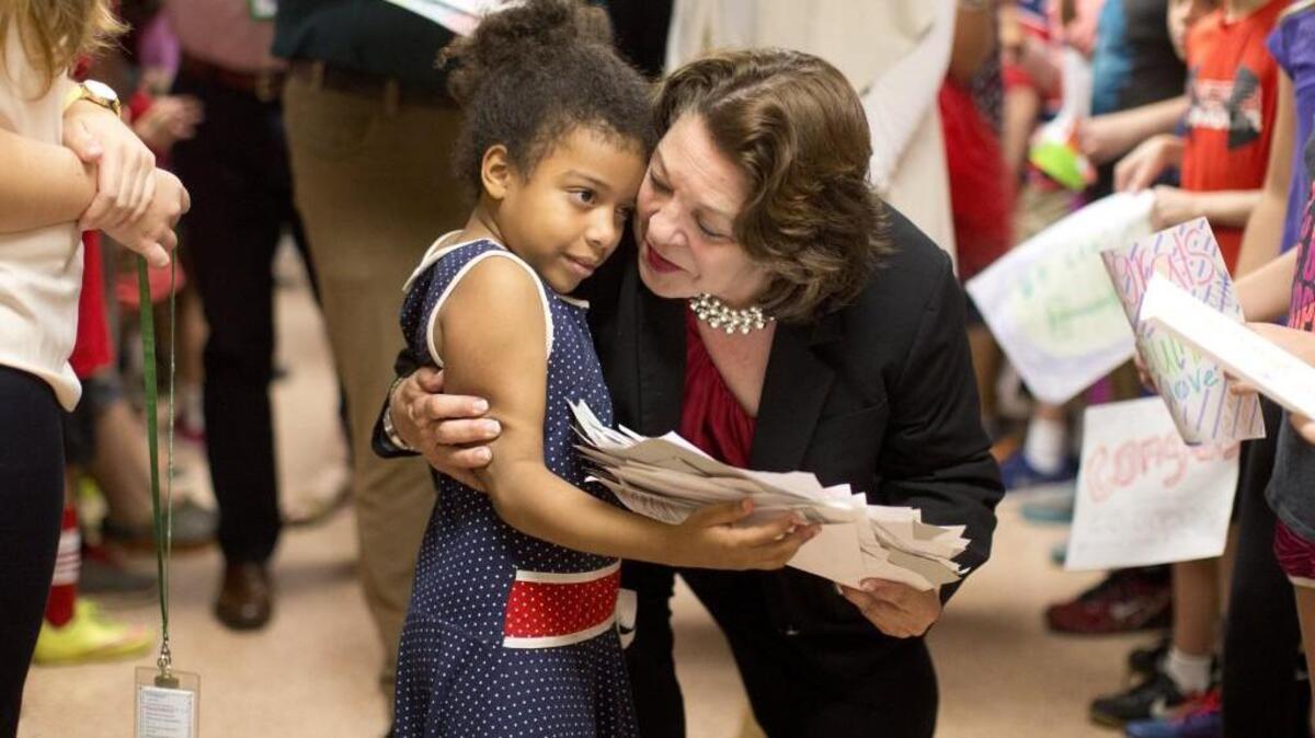 Tatiana Bradus, 7, hugs Principal Muriel Summers of Combs Elementary School during her celebration at the school Thursday morning October 6 in Raleigh.