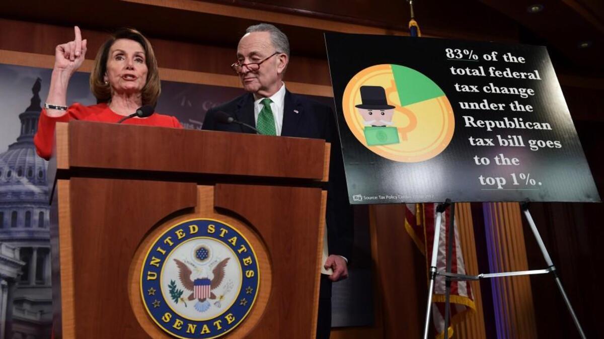 In this Dec. 20, 2017, file photo, House Minority Leader Nancy Pelosi of Calif., left, standing with Senate Minority Leader Sen. Chuck Schumer of N.Y., right, speaks at a news conference on Capitol Hill in Washington. Democratic candidates in the 2018 midterms plan to argue that the legislation favors the wealthy and breaks President Donald Trump and Republicans' promises to the middle class.