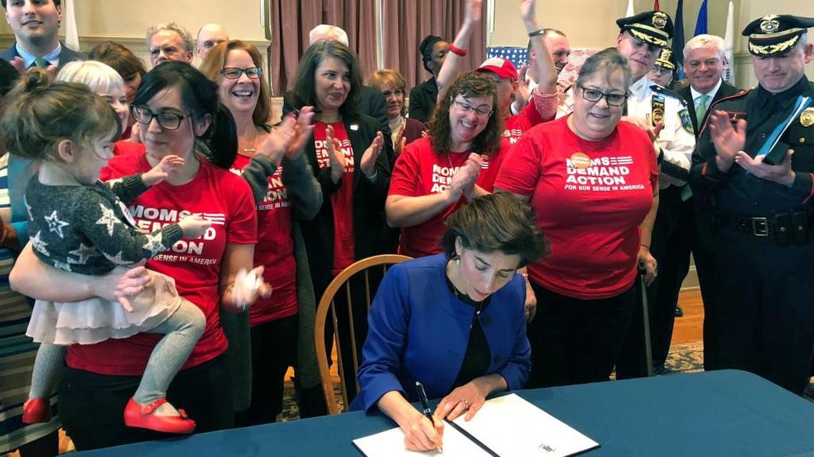 Cheers erupt as Rhode Island Gov. Gina Raimondo signs an executive order Monday, Feb. 26, 2018, in Providence, R.I., to establish a new policy allowing relatives or police to ask judges to temporarily strip gun rights from people who show warning signs of violence. California, Connecticut, Indiana, Oregon and Washington already have so-called “red flag” laws. More than a dozen other states are considering similar bills.