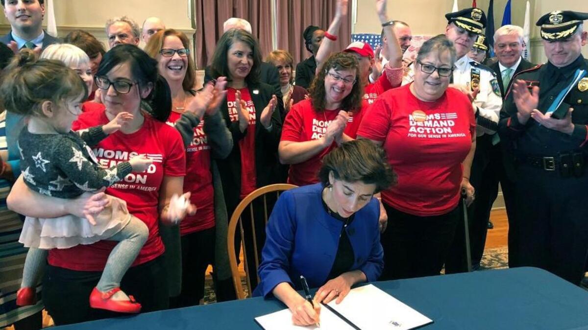 Cheers erupt as Rhode Island Gov. Gina Raimondo signs an executive order Monday, Feb. 26, 2018, in Providence, R.I., to establish a new policy allowing relatives or police to ask judges to temporarily strip gun rights from people who show warning signs of violence. Nineteen states and the District of Columbia have adopted laws allowing the temporary confiscation of firearms from people deemed dangerous to themselves or others.
