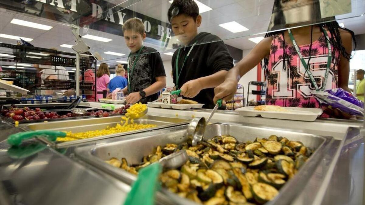 
The lunch program at Plaza Middle School in Kansas City, Mo., features a variety of healthy offerings. On Sept. 10, 2015, students Garrett Winheim, Evan Nguyen and Laniya Harris, left to right, select from items on the vegetable bar that include local organic zucchini, corn, grapes and a mixed salad.
