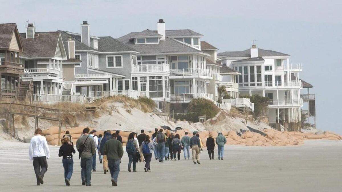 A group of Duke University students in 2003 walk past the imposing homes of Figure Eight Island to inspect beach erosion.