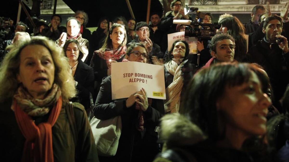 A woman holds a poster during a gathering in a show of support for Aleppo citizens, in Paris, Wednesday, Dec. 14. A cease-fire designed to allow for the evacuation of civilians and rebels crumbled Wednesday as government bombing resumed.