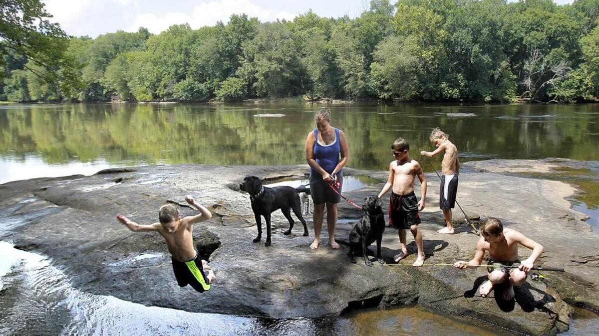(From left) The Hawkins family and their friend (from left) Sawyer Hawkins, Teresa Hawkins, Jackson Hawkins, Ian Bristow and Parker Hawkins, of Lillington, and the family dogs spend the afternoon at Fish Traps along the Cape Fear River in 2014.