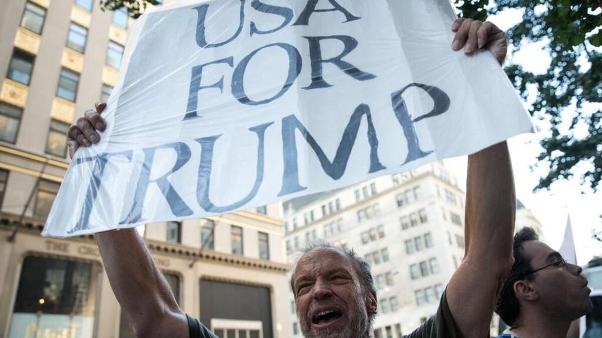 A supporter of Republican presidential candidate Donald Trump holds up a sign near people protesting against Trump and his policies outside of Trump Tower in New York City.