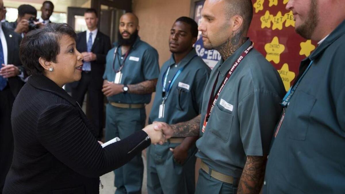 Attorney General Loretta Lynch, left, shakes hands with Derrick Cash during a visit to Talladega Federal Correctional Institution to highlight policies that aim to reduce barriers for formerly incarcerated individuals.