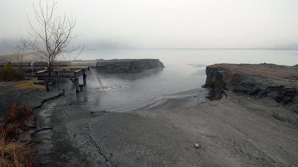 Coal ash slurry pours into the first of two settling ponds adjacent to the Riverbend Steam Station on Mountain Island Lake. Duke Energy disposes tons of coal ash from its power plants.