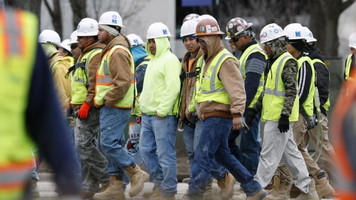 Charter Square construction workers cross South Street for their safety Monday morning, March 23, 2015 after three co-workers were killed and one seriously injured in a scaffolding collapse at the job site in downtown Raleigh.