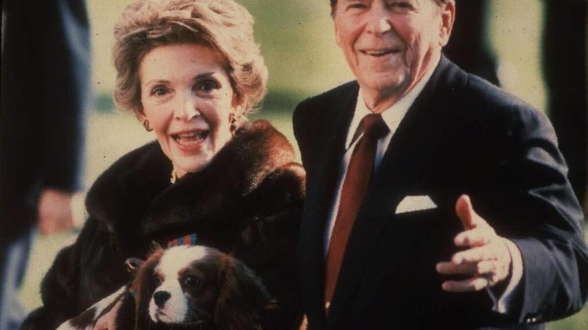 This December 1986, file photo shows first lady Nancy Reagan holding the Reagans’ pet Rex, a King Charles spaniel, as she and President Reagan walk on the White House South lawn. GOP vice presidential candidate Mike Pence says Donald Trump connects with Americans like Reagan did.