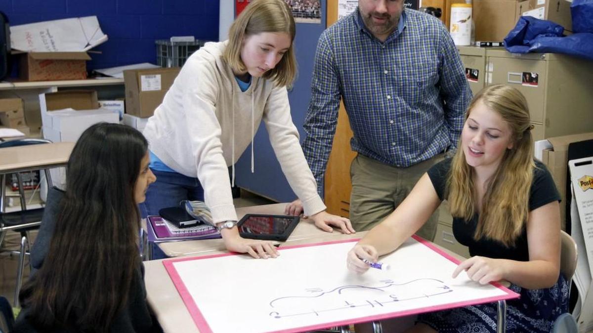 Students Kopal Gupta, left, Laurel Thomas, left center, and Karlyn Voltz, right, work on a problem as teacher Scott Maxwell, right center looks on in his Math III Honors STEM class at Athens Drive High School in Raleigh on Sept. 15, 2015. A new program proposed by Wake County State Sen. Chad Barefoot would give forgivable loans to teachers who commit to teaching science, technology engineering, math and special education.