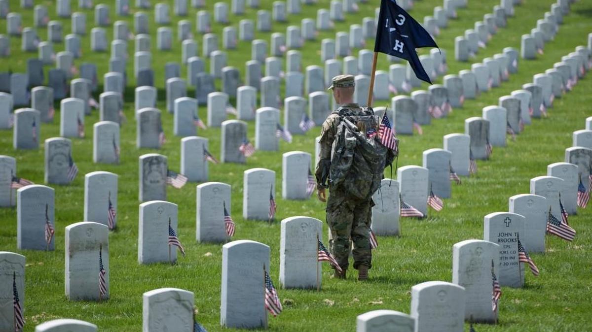 A member of the U.S. Army places American flags at graves at Arlington National Cemetery in Arlington, Virginia, in preparation for Memorial Day.