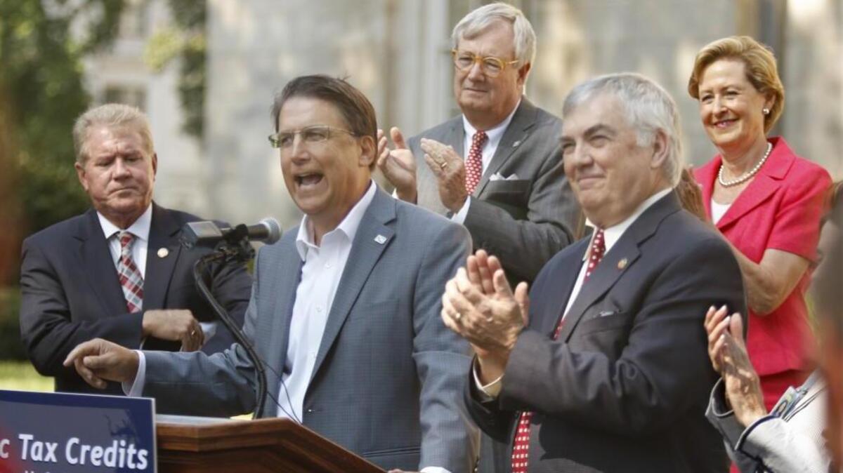 
Second from left and surrounded by members of his cabinet and state legislators, NC Governor Pat McCrory urges the NC House and Senate to get moving on HB 152, the New Historic Preservation Tax Credit bill stalled in a Senate committee since late March, 2015. McCrory, along with members of his cabinet and some state legislators spoke on the east side of the State Capitol Wednesday touting the strong points of reviving historic downtown areas across NC with the help of this revival of the Historic Tax Credit.
