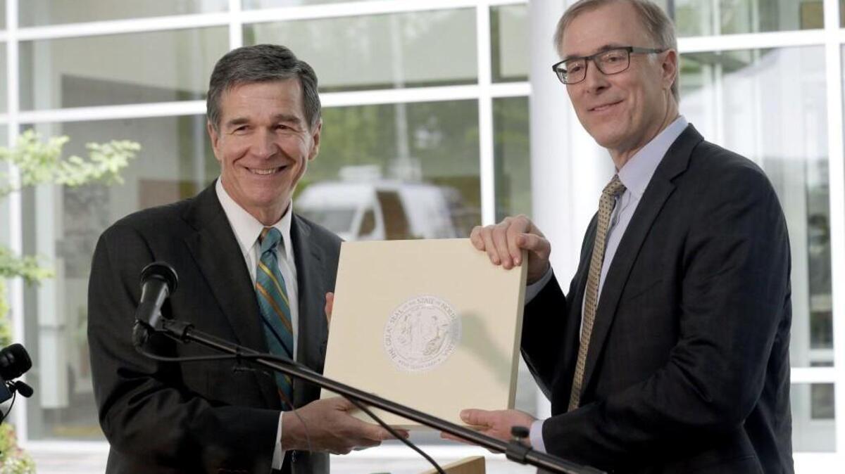 North Carolina Gov. Roy Cooper, left, and Wilson Ervin, Chair of the Credit Suisse Americas Foundation, pose with the State Seal during a news conference at Credit Suisse in Morrisville Tuesday, May 9, 2017. Credit Suisse plans to add up to 1,200 jobs at its North Carolina technology hub. The jobs projection comes five weeks after North Carolina partially repealed a state law limiting LGBT rights. (AP Photo/Gerry Broome)