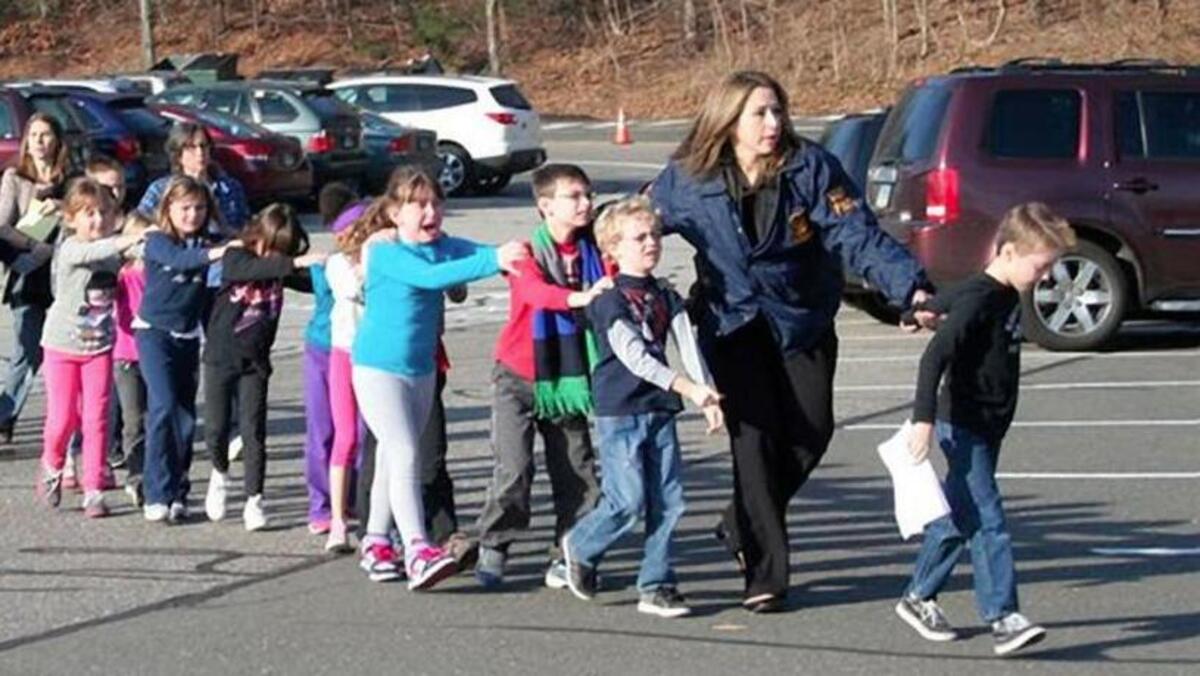 State police personnel lead children from the Sandy Hook Elementary School in this handout picture from the Newtown Bee, in Newtown, Connecticut, December 14, 2012.